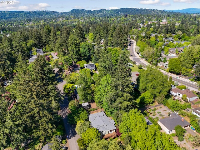 aerial view of property and surrounding area with a forest and nearby suburban area