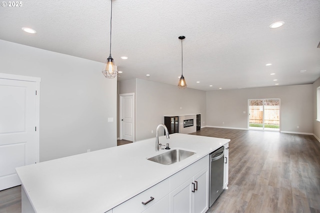 kitchen with an island with sink, sink, stainless steel dishwasher, and decorative light fixtures