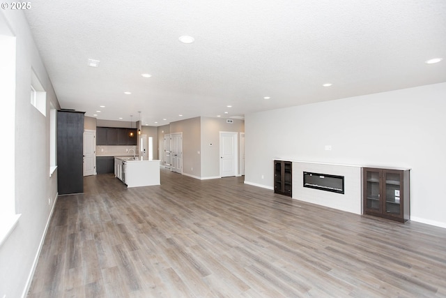 unfurnished living room with hardwood / wood-style flooring, sink, and a textured ceiling