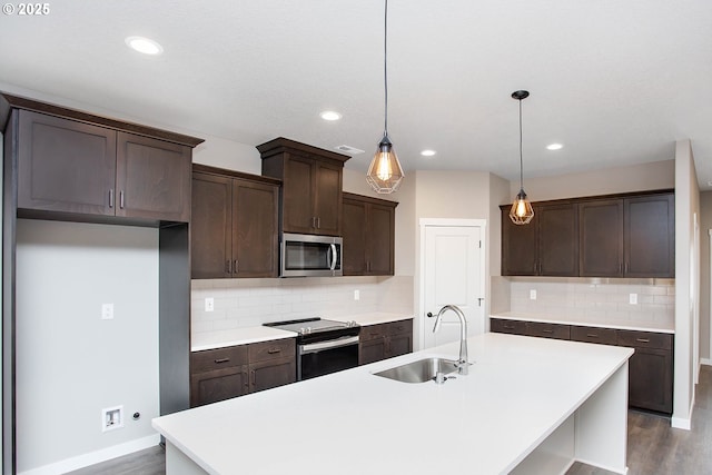 kitchen featuring sink, appliances with stainless steel finishes, an island with sink, pendant lighting, and decorative backsplash