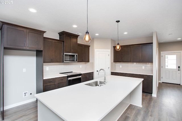 kitchen featuring pendant lighting, an island with sink, stainless steel appliances, and sink