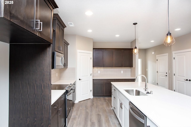 kitchen with hanging light fixtures, appliances with stainless steel finishes, sink, and dark brown cabinets