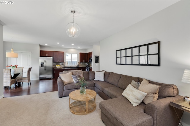living room featuring light colored carpet, recessed lighting, baseboards, and a chandelier