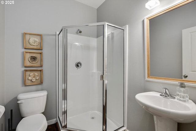 bathroom with a stall shower, toilet, and a sink