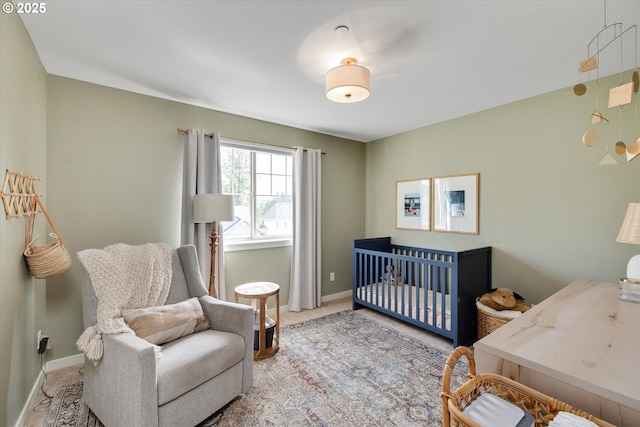 bedroom with carpet floors, baseboards, and a crib