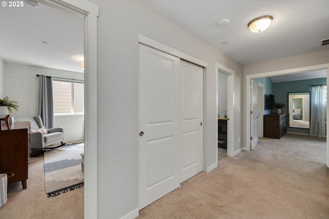 hallway with light colored carpet and baseboards