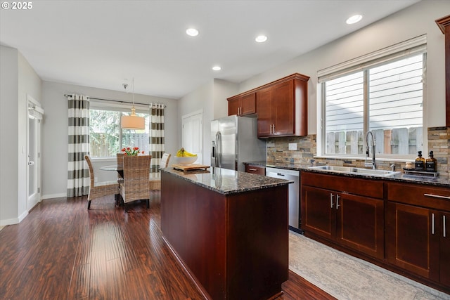 kitchen with a sink, appliances with stainless steel finishes, backsplash, dark stone counters, and dark wood-style floors