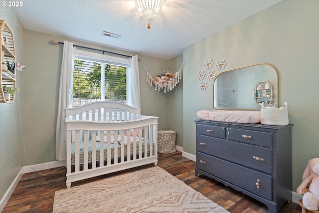 bedroom featuring a nursery area, baseboards, visible vents, and dark wood finished floors
