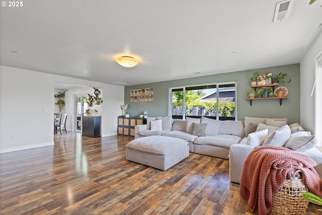 living room featuring baseboards, a textured ceiling, visible vents, and wood finished floors