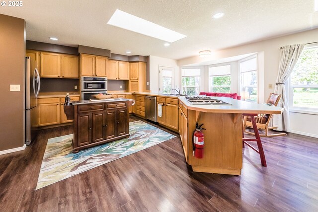 105 Sijota St, Gleneden Beach, OR 97388 - kitchen with a kitchen bar, a skylight, baseboards, appliances with stainless steel finishes, and a kitchen island