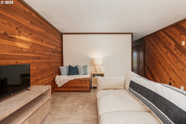 living area with wood walls, a textured ceiling, and crown molding