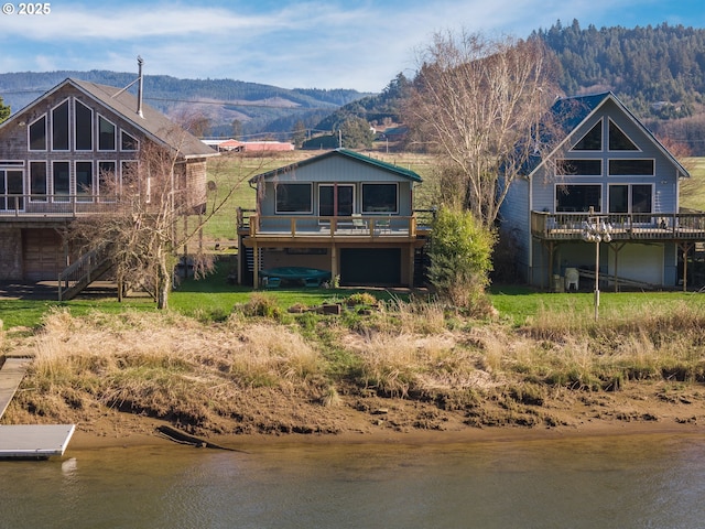 back of property with stairs and a deck with water view