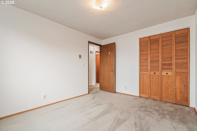 unfurnished bedroom with a textured ceiling, a closet, baseboards, and light colored carpet