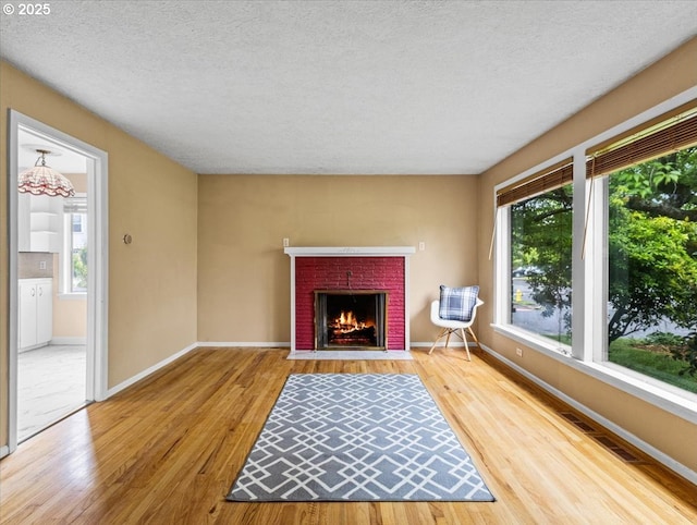 4501 NW Washington St, Vancouver, WA 98663 - unfurnished living room featuring wood finished floors, a textured ceiling, a brick fireplace, and baseboards