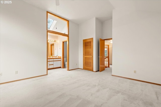 5002 SW Vacuna St, Portland, OR 97219 - unfurnished bedroom with high vaulted ceiling, light carpet, ensuite bath, baseboards, and a closet