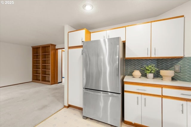 5002 SW Vacuna St, Portland, OR 97219 - kitchen with freestanding refrigerator, light countertops, white cabinetry, decorative backsplash, and baseboards