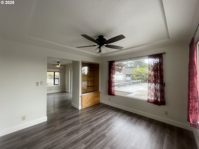 spare room featuring baseboards, a ceiling fan, dark wood-style floors, and a textured ceiling