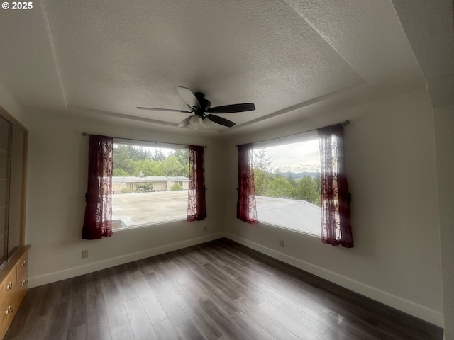 empty room with a textured ceiling, baseboards, dark wood finished floors, and a ceiling fan