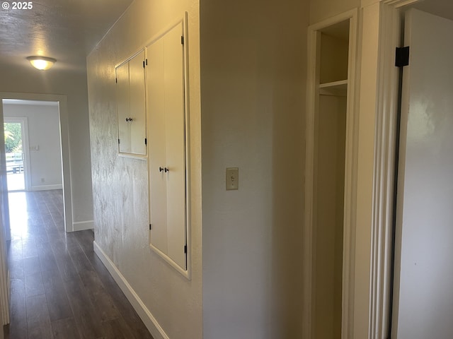 hall with dark wood-type flooring and baseboards
