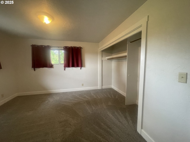 unfurnished bedroom featuring baseboards, dark carpet, and a closet