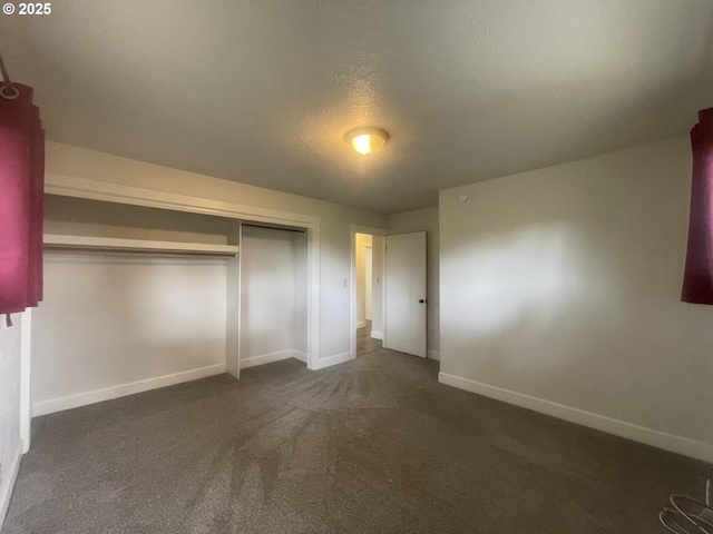 unfurnished bedroom featuring baseboards, dark colored carpet, and a closet
