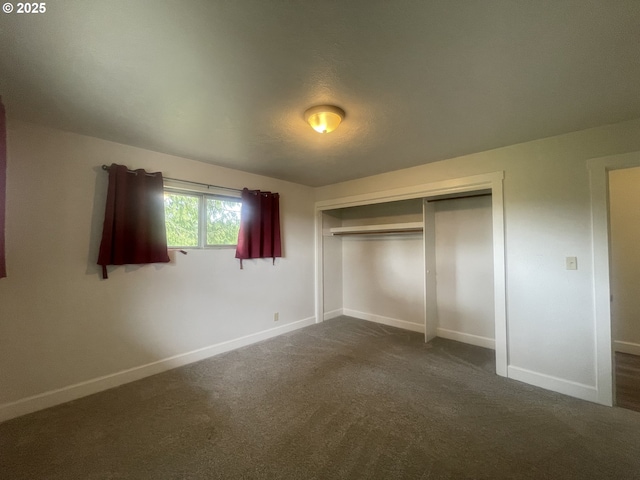 unfurnished bedroom featuring baseboards, a closet, and dark carpet