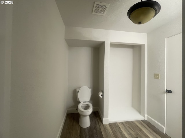 bathroom featuring wood finished floors, baseboards, and toilet