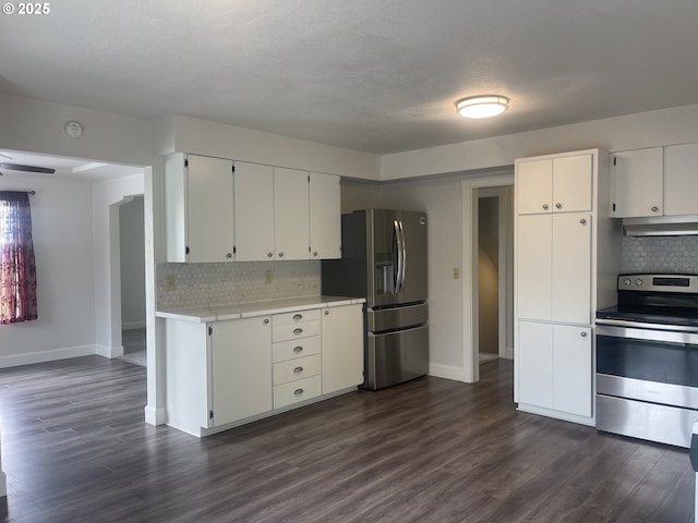 kitchen featuring appliances with stainless steel finishes, under cabinet range hood, tasteful backsplash, and dark wood-type flooring