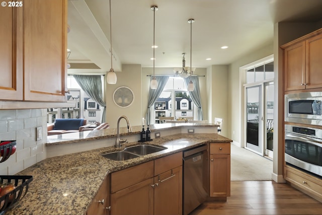 707 N Hayden Island Dr Unit 413, Portland, OR 97217 - kitchen with a sink, brown cabinets, stone countertops, wood-type flooring, and appliances with stainless steel finishes