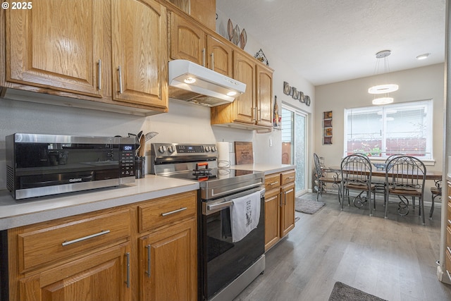 kitchen featuring a textured ceiling, hanging light fixtures, stainless steel range with electric cooktop, and light wood-type flooring