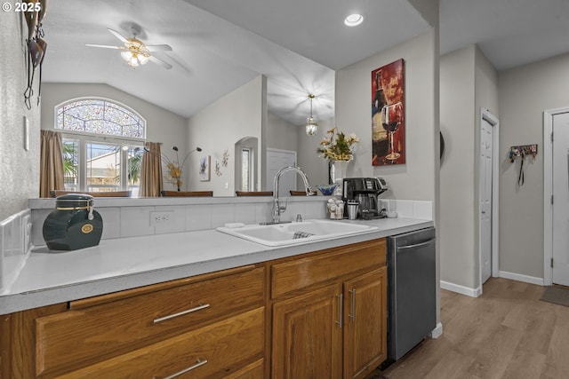 kitchen with sink, ceiling fan, dishwasher, vaulted ceiling, and light wood-type flooring