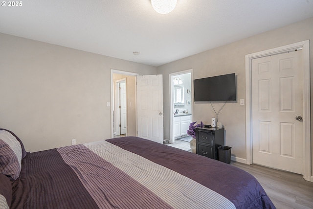 bedroom with ensuite bath and light hardwood / wood-style floors