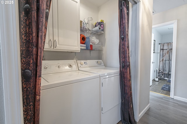 washroom with cabinets, light hardwood / wood-style floors, and washer and dryer