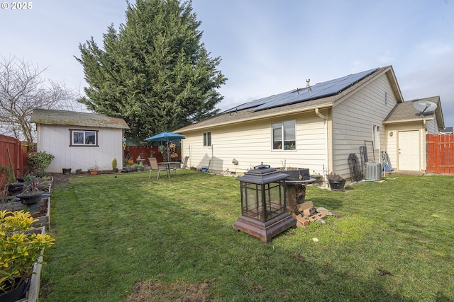 rear view of property with an outdoor structure, a lawn, central AC unit, and solar panels