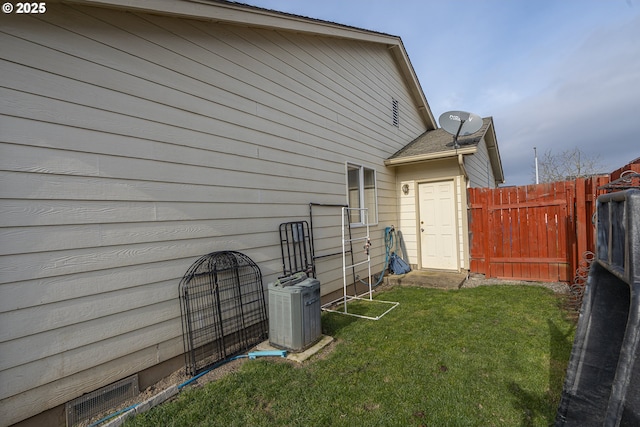 rear view of house featuring central AC and a lawn