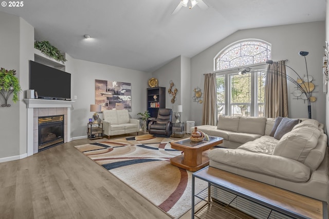 living room with a tiled fireplace, lofted ceiling, hardwood / wood-style floors, and ceiling fan