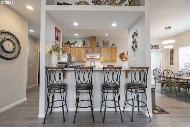 kitchen with a kitchen bar, kitchen peninsula, and hardwood / wood-style floors