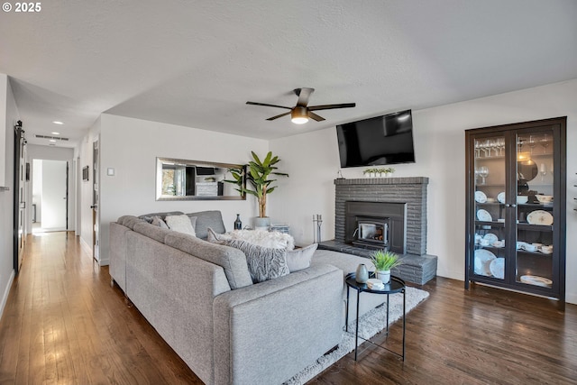 living room featuring dark hardwood / wood-style flooring, ceiling fan, a textured ceiling, and a brick fireplace