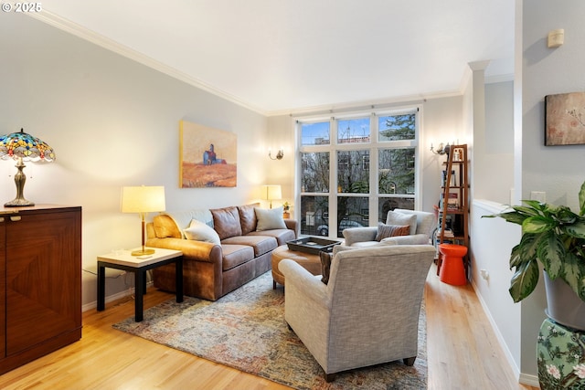 living area with light wood-style floors, baseboards, and ornamental molding