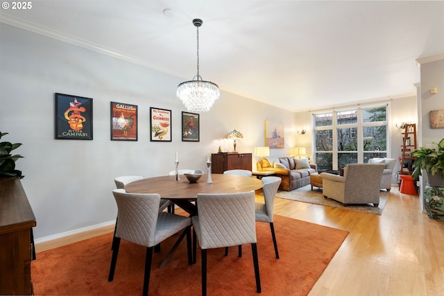 dining area featuring crown molding, baseboards, a chandelier, and light wood-style floors