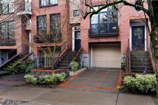 exterior space featuring an attached garage, aphalt driveway, and brick siding