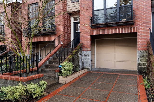 entrance to property featuring a garage, driveway, and brick siding