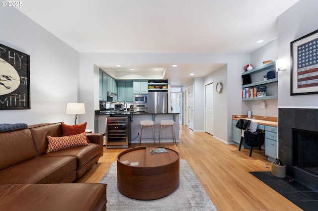 living room with light wood-type flooring, recessed lighting, wine cooler, and built in study area