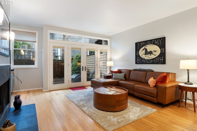 living room with french doors, a fireplace, wood finished floors, and baseboards