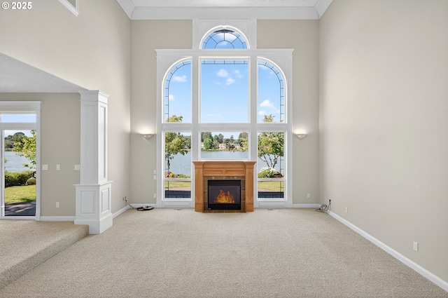 21401 NE Shore Dr, Fairview, OR 97024 - unfurnished living room featuring ornate columns, a towering ceiling, carpet flooring, a glass covered fireplace, and a water view