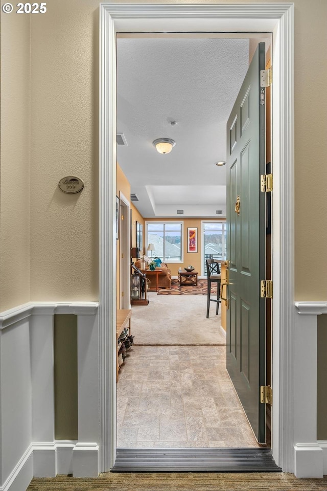 entryway with a tray ceiling, carpet flooring, and baseboards