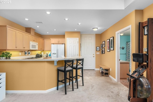 kitchen featuring light countertops, light colored carpet, visible vents, white appliances, and a peninsula