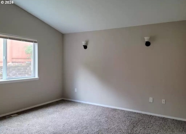 carpeted spare room with vaulted ceiling and baseboards