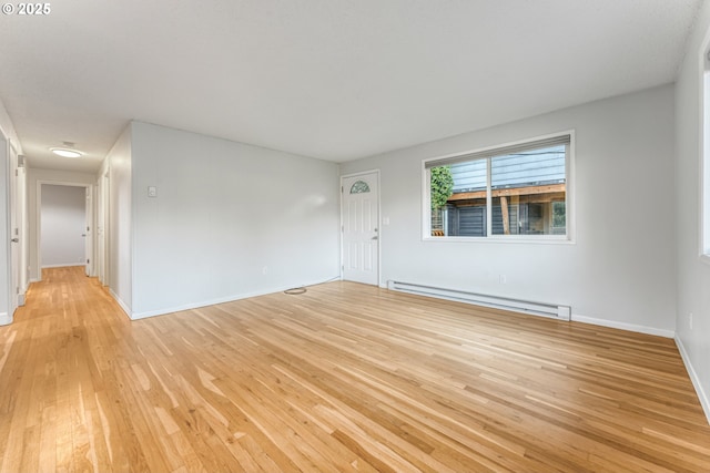 unfurnished room with baseboard heating and light hardwood / wood-style floors