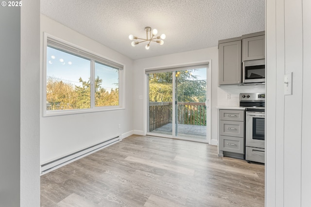 kitchen featuring gray cabinetry, a chandelier, light hardwood / wood-style flooring, appliances with stainless steel finishes, and a baseboard heating unit